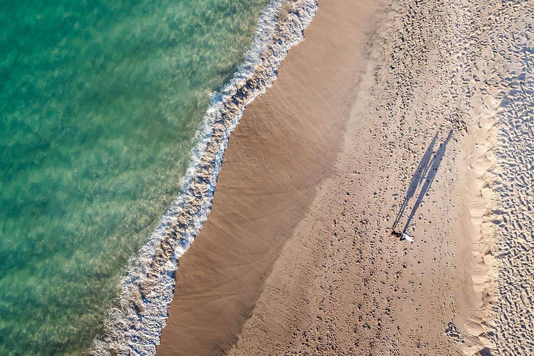 Aerial beach portrait Tamarindo – couple walking along sandy shoreline