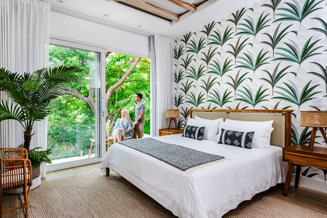 Tropical bedroom photography Costa Rica – airy bedroom with palm leaf wallpaper and garden view