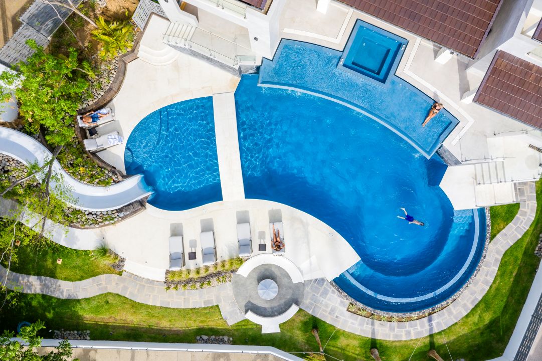 Aerial lifestyle photography Costa Rica – drone view of villa pool surrounded by palm trees