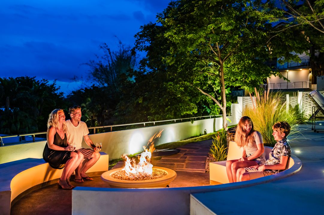 Evening lifestyle photography Costa Rica – couple relaxing by outdoor fire pit under tropical sky