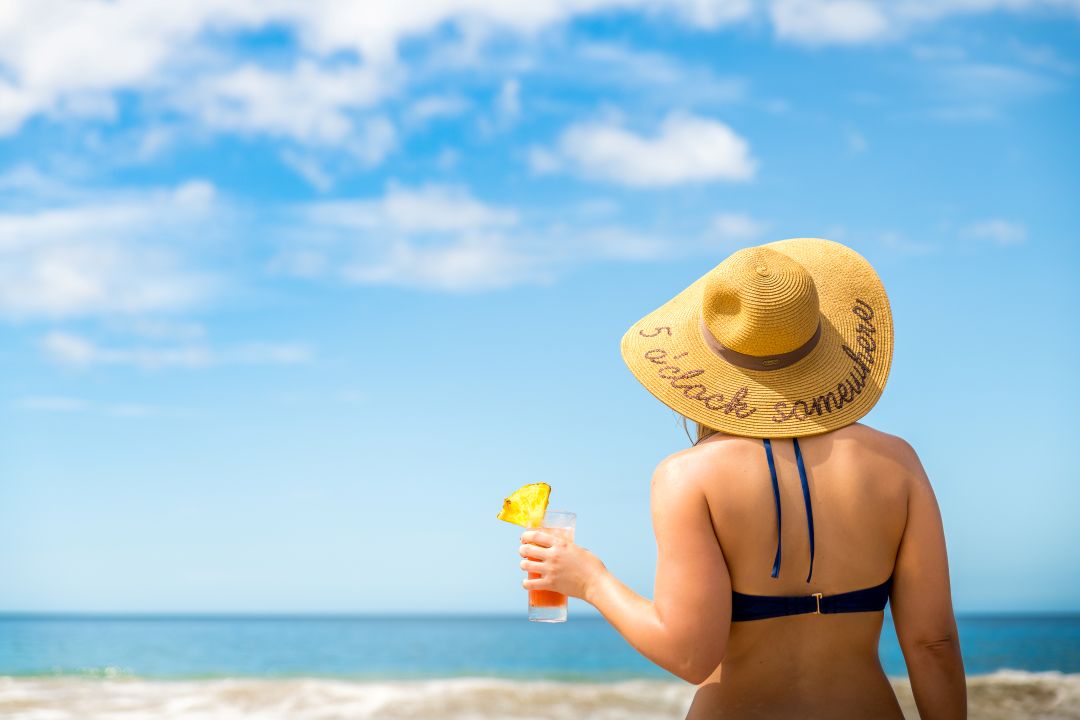 Costa Rica lifestyle photo – woman in sun hat holding drink and admiring the ocean view