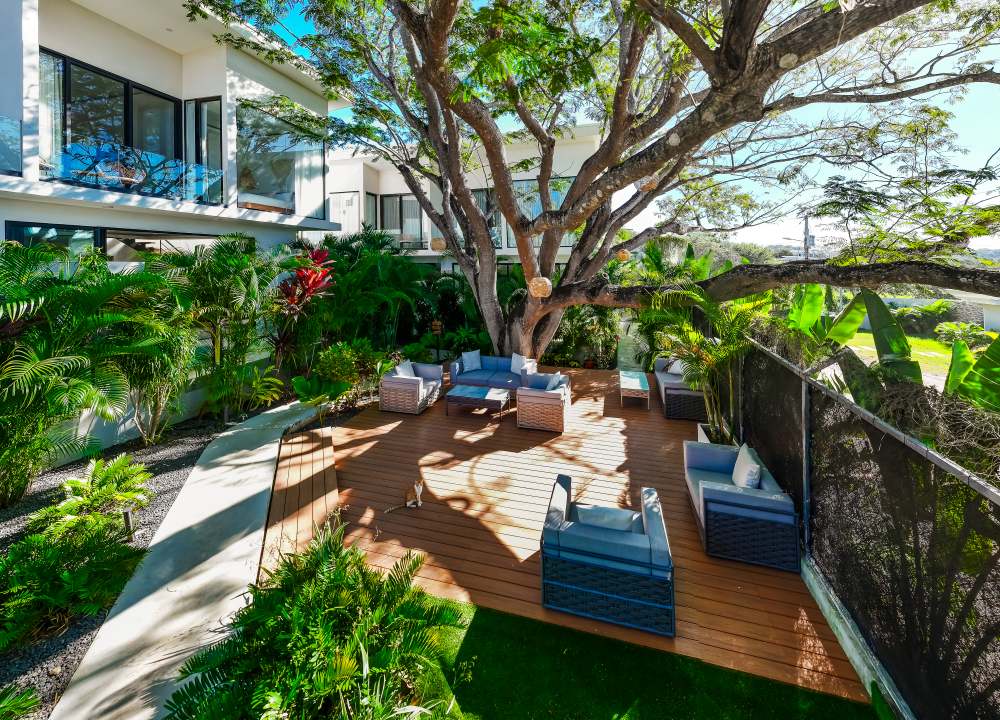 Vacation rental photography Costa Rica – tropical outdoor terrace with modern furniture under a large tree