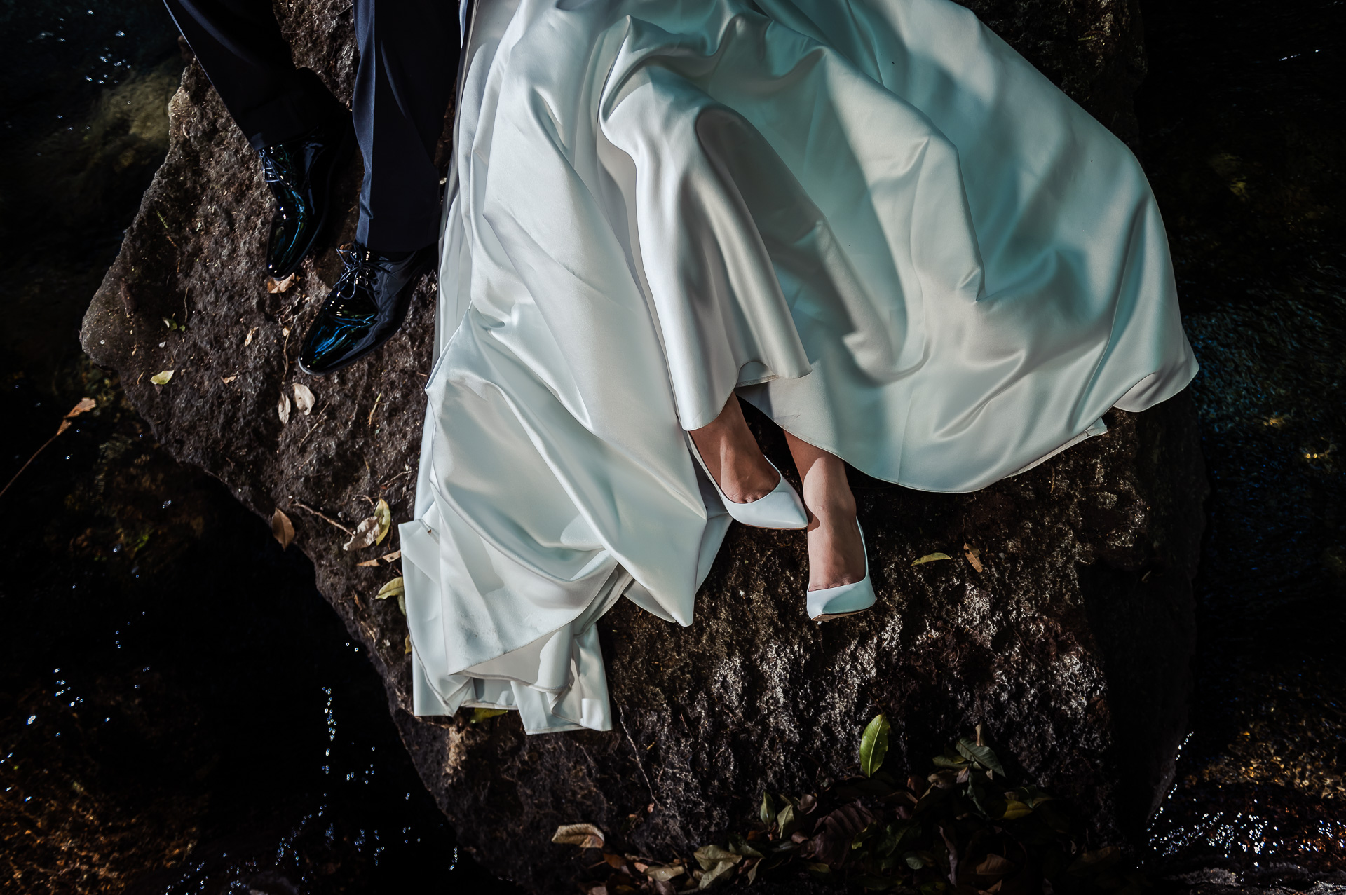 Close up on shoes, dress and pants of wedding couple on a rock in Costa Rica