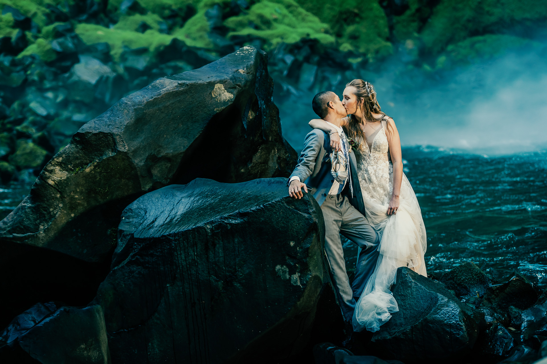After the wedding a couple kiss on a rock next to the Arenal waterfall, Costa Rica